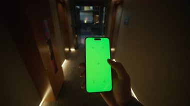 Kafkas asıllı bir erkeğin otelin karanlık koridorunda yeşil ekranlı akıllı telefonu tuttuğu görüntüler. Geceleri kapılarla koridorda yürüyen tanınmayan genç bir adam. İçeride. Yatay çekim. Model