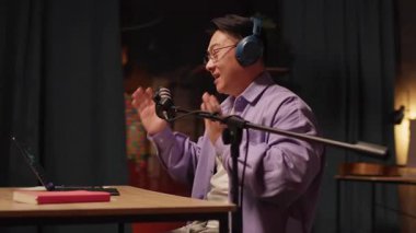 Asyalı içerikli yaratıcı dizüstü bilgisayarda kulaklıkla konuşuyor ve gece yayın stüdyosunda mikrofon röportajı yapıyor. - Eve. 360 derece. Kamera hareket ediyor