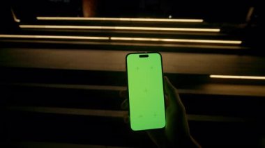 Akşamları yeşil ekran merdivenli akıllı telefon kullanan, tanımlanamayan genç beyaz adamın yakından çekimi. Adam dışarıda mesajlaşıyor. Mokrom anahtarı.