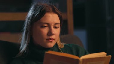 Akşamları evdeki sandalyede oturmuş kitap okuyan çekici bir kadının portresi. Romantizme odaklanmış