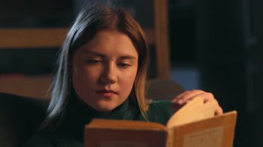 Genç ve güzel bir kadın kitap okuyor. Akşamları evdeki kanepede oturuyor. Romantizme odaklanmış