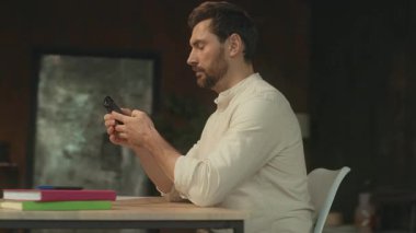 Masada oturan sakallı, ciddi bir genç adam sosyal medyada telefon konuşması yapıyor. Modern ofis. Kamera hareket ediyor. 360 Derece