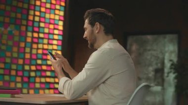 Çekici iş adamı masasında oturmuş, telefonda yazışırken gülümsüyor. Modern ofis. Sosyal medya. Kamera hareket ediyor. 360 Derece