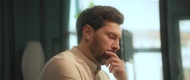 Masada oturan çekici sakallı adam ofiste ciddi görünüyor. Düşünüyorum. Kamera hareket ediyor. 360 Derece