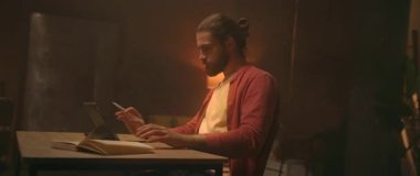 Masada oturan yakışıklı, beyaz bir adamın dijital tabletle kadın resmi çizdiği bir fotoğraf. Stylus kullanan adam. Modern oturma odası. Uzaktan çalışma konsepti. Serbest İşçi rutini