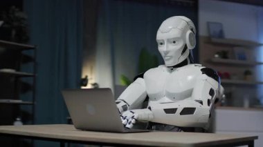 Masada oturan ve dizüstü bilgisayar kullanan modern beyaz robotun görüntüsü. Klavyede Android daktilo. Robot insansı metin yazarı ve serbest yazar olarak çalışıyor. Yapay zeka beyin. Yapay