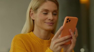 Gülümseyen kadın, evde otururken akıllı telefonu kullan. Sosyal medya kayıyor. Kamera hareket ediyor. 360 derece