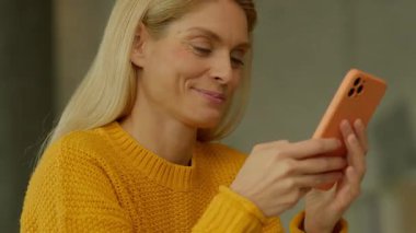 Gülümseyen kadın evde otururken akıllı telefon kullan. Sosyal medya kayıyor. Uykum geldi. Kamera hareket ediyor. 360 derece