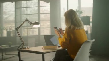 İşçi çekici kadın ofiste telefon yazma notları kullanıyor. Yoğun bir iş günü. Düşünüyorum. Kamera hareket ediyor. 360 derece