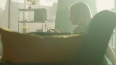 Evdeki kanepede oturan bir kadın tablet bilgisayar kullanarak üzgün hissediyor. Odada güneş ışığı var. Dinlenme zamanı. Düşünüyorum. Kamera hareket ediyor. 360 derece