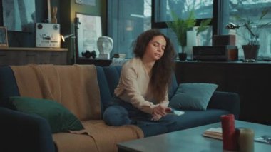 Kanepede oturan, tebligat duyan, akıllı telefon alan ve oturma odasında mesajları kontrol eden güzel beyaz bir kadın. Kötü haberlerle mesaj okuyan mutsuz bir kızın portresi. Kapalı