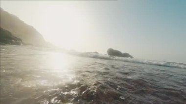 Fırtınalı mavi deniz manzarası birinci şahıs çekiminde. Kayalık kıyı şeridi, fırtınalı okyanus ve açık gökyüzü dramatik bir şekilde görülüyor. Yaz. Yolculuk.