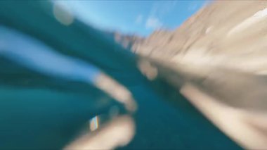 FPV güzel sakin deniz suyuna dalıyor. Mavi kristal temiz su yüzeyi, dalgalar ve güneş ışığı. Harika bir sahil ve deniz kenarı. Yüzme.