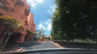 Güneşli bir günde güzel tropikal şehir manzarası boyunca araba sürmek. Sürücü arabasının ön camı çarpıcı İslami mimari ve palmiye sokaklarına bakıyor.