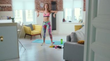 Çekici fit esmer kadın paspas üzerinde egzersiz yapıyor. Parlak oda fitness eğitimi alıyor. Spor giyiniyor, sağlıklı kız sağlıklı atlet esnekliği yavaş çekimde.