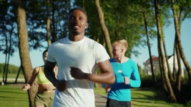 Gelecekteki maraton için birlikte koşan üç harika atletik insan grubu halka açık parkta fiziksel yoğun egzersizler yapıyorlar. Koşu takımı. Üçlü çalışma.