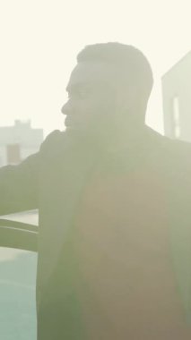 Uzağa dikkatlice bakan, canlı bir şehir ortamında derin derin düşünen bir adamın profili.