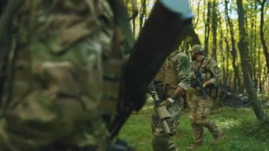 Orman askerleri kamuflaj üniformaları ve silahlı üniformalarıyla yavaşça etrafa bakınıyorlar. Miğferli askerler. - Savaş. Korunma. Yavaş çekim