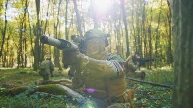 Koruyucu kamuflaj üniformalı Ukraynalı askerler güneş ışığı ormanında silahlı. Kasklı askeri keskin nişancı saldırıyor. Yavaş çekim