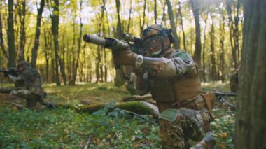 Ormanda Ukrayna askerleri koruyucu kamuflaj üniformalarıyla ormanda yere düşerler. Kasklı askeri keskin nişancı saldırıyor. Yavaş çekim