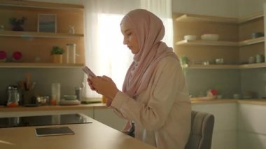 Tesettürlü çekici bir kadın, gün ışığında sosyal medyada telefon kullanıyor. Gülümseyerek mutlu ol. Kamera hareket ediyor. 360 derece