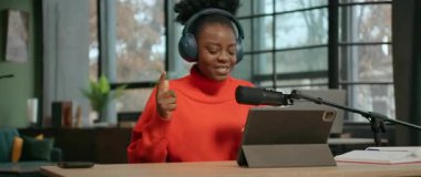 Enerjik hareketler, neşeli Afrikalı Amerikalı gülümseyen radyo sunucusunun mikrofonda oturup radyo dinleyicileriyle konuşmasını takip ediyor. Kulaklıklı mutlu genç bir kadının görüntüsü. 360 derece ofis