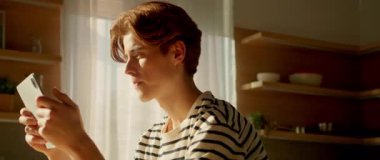 Evde dijital tablet kullanan düşünceli beyaz bir adamın görüntüsü. Çizgili tişörtlü, kızıl saçlı, oyuncak ekranına dokunan yakışıklı bir adam. Uygulamalar, bildiriler. İnternet iletişimi