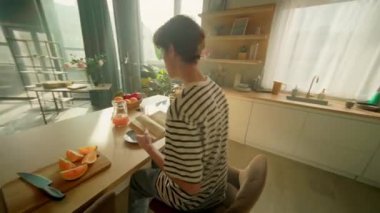 Beyaz adamın kahvaltı masasında otururken çekilen görüntülerini takip ediyorum. Genç adam tabağa portakal dilimleri koyup kitap okuyor. 360 derece mutfak. Sabah rutini konsepti