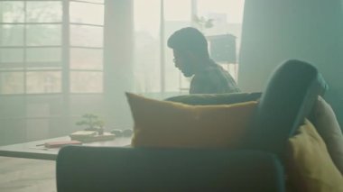 Gözlüklü genç adam evdeki kanepede oturan tablet bilgisayar kullanıyor ve mutlu oluyor. Düşünüyorum. İletişim. Kamera hareket ediyor. 360 derece