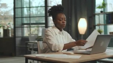 Sandalyede oturan Afro-Amerikalı iş kadını ofiste bilgisayarla çalışıyor. Yorgun hissediyorum. Kamera hareket ediyor. 360 derece