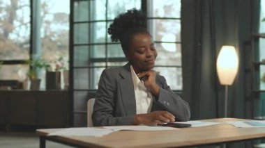 360 derece ofis. Akıllı telefondan titreyen kafasıyla masada oturan odaklanmış bir iş kadını. İş yerinde masa başında kağıtlarla oturan genç bir kadın. Kamera hareket ediyor. E-ticaret konsepti. Kapalı