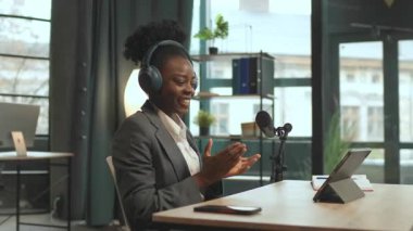 360 derecelik mutlu Afrika kökenli Amerikalı bayan radyo sunucusu dijital tablette radyo izleyicileriyle sohbet ediyor. Kamera hareket ediyor. Mikrofonlu genç bir kadın. Kaydediyor
