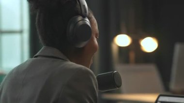 360 derece ofis. Pozitif enerjik genç Afrikalı Amerikalı kadın ofiste çalışırken masasında oturuyor. İş elbiseli Bunette kız ofiste podcast kaydediyor. Çekim etrafında hareket eden izleme