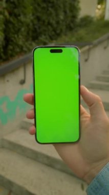 Dışarıdaki yeşil ekrana bakan akıllı telefonlu beyaz bir adamın yatay görüntüsü. Sokakta yürüyen adam. Modern binaya karşı cep telefonu kullanan bir işadamı. Mahalle. Açık havada.