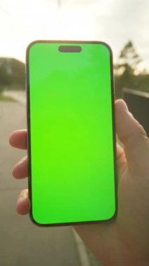 Şehirde navigatör kullanan tanınmayan bir adam. Merdivenlerin bulanık arka planında yeşil ekranlı akıllı telefonu tutan bir erkeğin görüntüsü. Telefondaki adam mesaj okuyor. Varış konsepti. Açık havada.