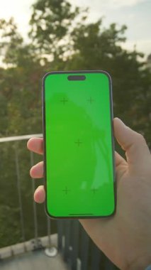 Dışarısı yeşil ekranlı akıllı telefonu tutan adamın görüntüsü. Özel sektörde yürürken telefonla mesajları kontrol eden bir adam. Bulanık görüş. Teknoloji ve modern yaşam tarzı. Açık havada.