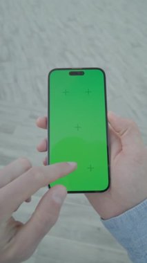 Yeşil ekranlı, el ele tutuşan ve dikey olarak telefonu kaydıran. Arka plandaki merdivenlerde.