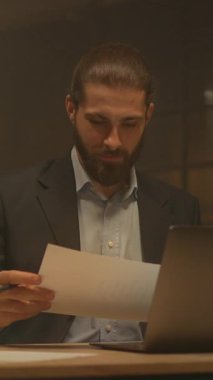 Akşam vakti sakallı genç işadamı masaya oturup kağıtlarla çalışmayı düşünür. Gece ofisindeki bilgisayarı kullan. İşine odaklan.