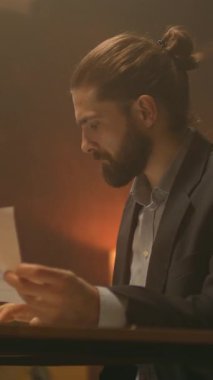 Gece ofisindeki kızgın işadamı masa başında oturup evrak işleriyle kafayı bozmuş ve stresli hissediyor. Telefonda gergin konuş.