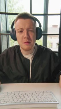 Kulaklıklı yakışıklı genç adam bilgisayarda çalışıyor müzik dinliyor ve dans ediyor. Pozitif iş adamının portresi