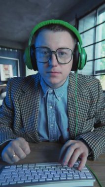 Gözlüklü ve kulaklıklı adam klavyede bilgisayar kullanıyor gergin ve sinirli. Vay be. Ofis ya da daire