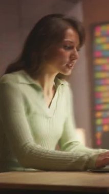 Çalışmayı bitiren yorgun genç bir kadın, dizüstü bilgisayarı ve defteri kapatıyor. Akşamları masada oturan güzel bir esmerin görüntüsü. Uzaktan kumandalı iş. Kamera hareket ediyor. Modern çağdaş