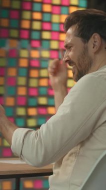 Masada oturan mutlu iş adamı ekranda dizüstü bilgisayar kullanıyor gülümsüyor ve ofiste dans ediyor. Tatmin oldum. Kamera hareket ediyor. 360 Derece