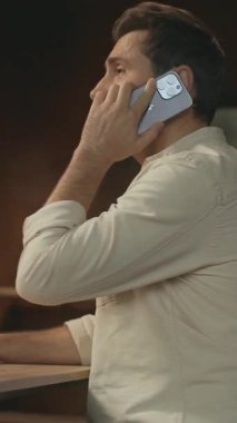 Gülümseyen işadamı masada oturmuş telefonla konuşuyor. Akıllı telefondan konuşuyor. Mutlu ol. Modern ofis. Kamera hareket ediyor. 360 derece