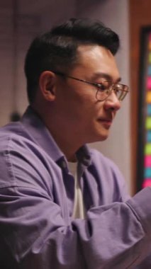 Gözlüklü Asyalı ciddi bir genç adam gece vakti sosyal medyada cep telefonuyla sohbet ediyor. 360 derece. Kamera hareket ediyor