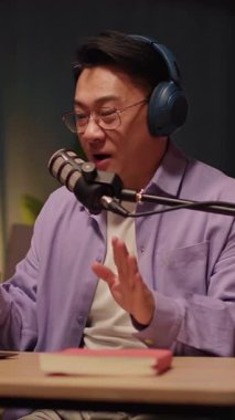 Mutlu gülümseyen Asyalı gözlüklü adam cep telefonu kullanıyor. Gece evde sosyal medya sohbeti yapıyor. 360 derece. Kamera hareket ediyor