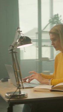 İş kadınının görüntüsü ciddi görünüyor. Dizüstü bilgisayar ve defter ofisteki masada. Yoğun bir iş günü. Kamera hareket ediyor. 360 derece