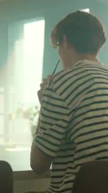 İz sürme sahnesinde hareketli enerji. Video aracılığıyla konuşurken sarı akıllı telefon kullanan gülümseyen beyaz bir genç. Mutfaktaki kahvaltı masasında oturan neşeli duygusal adam. 360 derece zaman