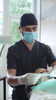 Modern klinik asistanları ve tıbbi maskeli dişçiler diş tedavisi için diş aletleri bulundururlar. Hydience ve sağlıklı.