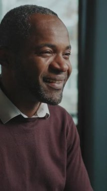 Bilgisayarın başında oturan düşünceli Afrikalı adamın portresi evde çalışırken ekrana bakıp mesaj okumaya odaklanmış. Gülümseyen işadamı işini seviyor. İçeride. Bulanık arkaplan